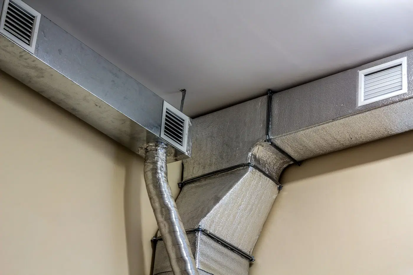 Exposed insulated air-conditioning ducts and ceiling-level ventilation grilles.